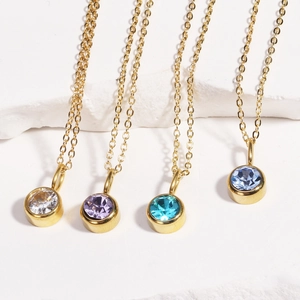 Close-up of four gold birthstone necklaces with crystal, purple, and blue round gems