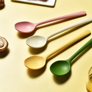 Set of four colorful silicone spoons in pink beige yellow and green for kids and dining