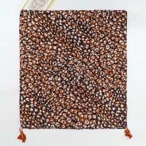 Detail of orange tassels on ethnic leopard print scarf with deep blue and orange spots