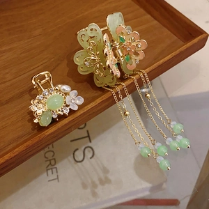 Detail of floral hair claw with green tassels and pearls on a wooden tray
