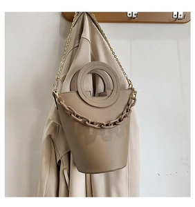 Detail of khaki bucket bag showing round handle, PU leather texture and resin chain