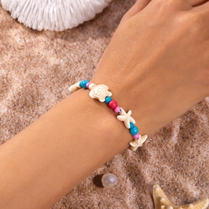 Close-up of Bohemian beach bracelet with colorful beads and starfish charms on sand