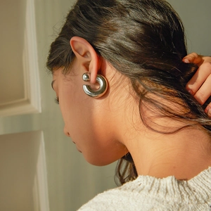 Polished silver C-shaped stainless steel earrings with ball backs on model