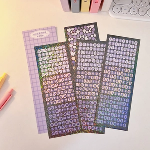 Detailed view of colorful laser alphabet stickers on a white desk with stationery items