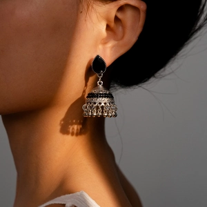 Close-up of vintage silver Jhumka earrings with black rhinestones on female model