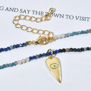 Detail of bohemian tourmaline stone necklace with gold heart evil eye pendant and clasp
