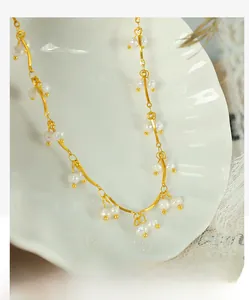 Detail of freshwater pearl necklace with gold wavy metal bars on shell display plate