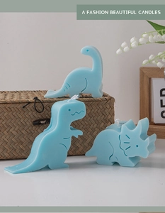 Detailed view of three light blue dinosaur scented candles with a matte wax texture
