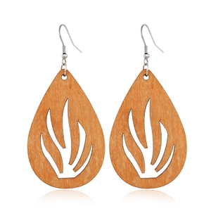 Macro detail of teardrop-shaped hollow wooden earrings with brown geometric patterns