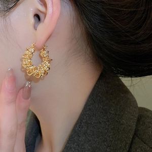 Gros plan de la boucle d'oreille torsadée plaquée or avec pierres de zircone étincelantes