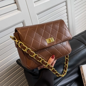 Brown quilted crossbody bag with gold chain strap and metal lock shown in model's hand