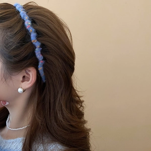 Detail of blue knitted wave headband with colorful yarn specks on a female model
