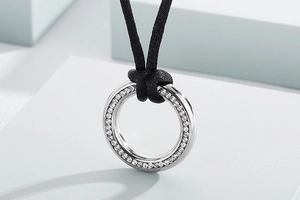 Close-up of silver circular pendant with crystals on black velvet cord necklace