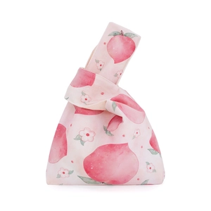 Detail of knot wrist bag featuring pink peach watercolor print on cream cotton fabric