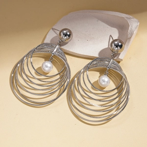 Detailed view of layered silver geometric circular earrings with a central pearl drop