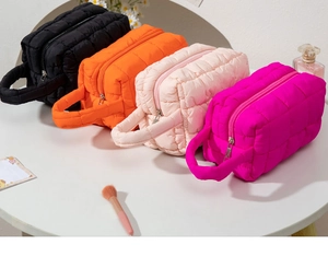 Detailed view of quilted makeup bags in black, orange, pink and rose red colors