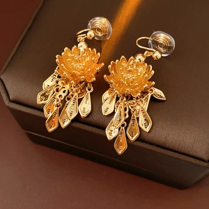 Detail of gold-plated lotus tassel earrings with leaf charms on a jewelry box