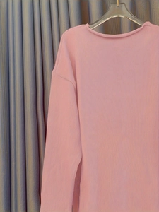 Détail de la texture d'un pull rose à manches longues en maille côtelée verticale