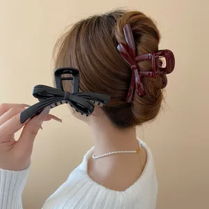 Elegant bow hair claw clips in black and wine red shown on a model with hair accessory
