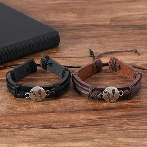Close-up of black and brown braided leather baseball bracelets on a wooden surface