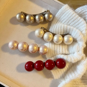 Detail of four elegant faux pearl spring hair clips in champagne, white, pink and red