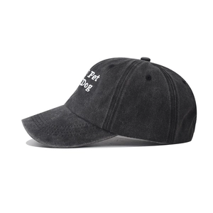 Close-up of the white 'Pet Dog' embroidery on a washed black cotton baseball cap