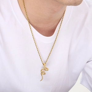 Detail of 18k gold snake pendant necklace featuring textured coiled design on a model