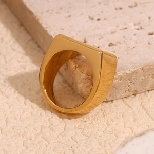 Minimalist 18K gold plated stainless steel signet ring on a beige textured stone