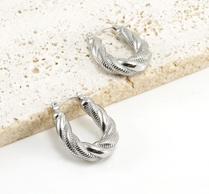 Detail of twisted silver hoop earrings with dual texture on travertine display stand