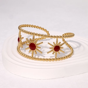 Vintage golden hollow sunflower bangle with red enamel inlay on a white platform
