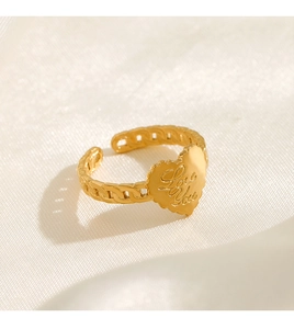 Close-up of golden heart ring engraved with Love You text on a silk fabric background