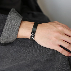 Close-up of black stainless steel chain bracelet with a flat metal plate on man's wrist