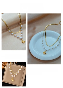 Detail of layered gold snake chain with irregular pearls and a butterfly pendant