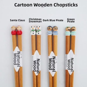 Detail of four pairs of natural wood chopsticks with hand-painted cartoon doll heads