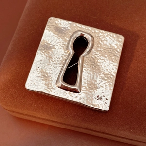 Macro view of vintage square keyhole brooch with a hand-hammered textured silver finish