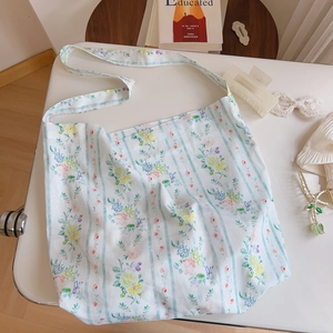 Floral cotton tote bag with light blue stripes and wide shoulder strap on white desk