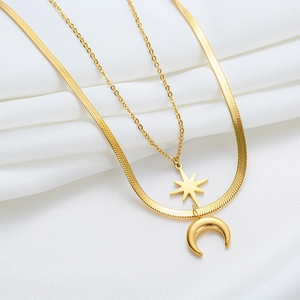 Double-layered gold titanium steel necklace featuring star and moon pendants on white silk