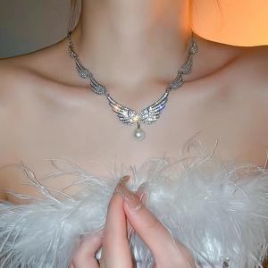Detailed view of silver angel wing necklace with sparkling zircons and pearl on a model
