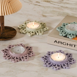 Detailed view of Morandi color floral tea light holders on a marble surface with warm lighting