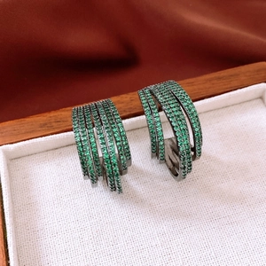 Gros plan de boucles d'oreilles multicouches en forme de C avec zircons verts et métal