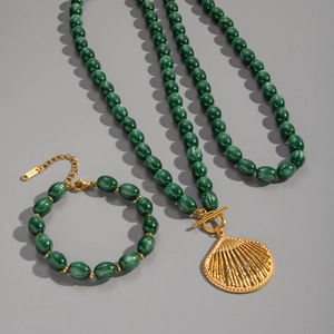 Detailed view of dark green beaded necklace and bracelet set with golden shell pendant