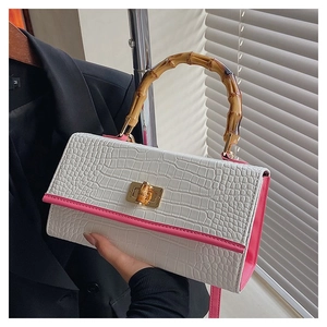 Detail of white crocodile pattern handbag featuring bamboo handle and golden lock clasp