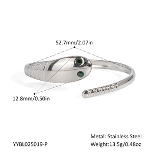 Detailed view of silver snake bangle with green stone eyes and spiral scale texture