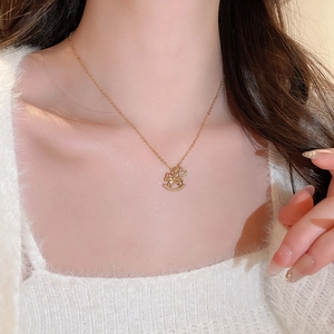 Detail of gold-plated rocking horse necklace with clear stones on a model