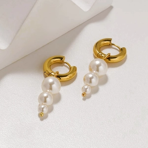 Detalle de pendientes de aro bañados en oro de 18K con tres perlas colgantes graduadas