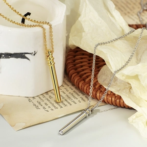 Chic gold and silver bamboo cylinder pendant necklaces with zircon crystals on a marble base