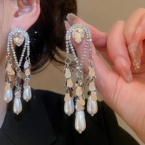 Detail of drop pearl earrings with sparkling rhinestones and silver tassels on model