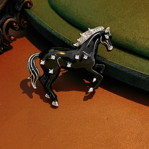Macro detail of vintage horse brooch with black enamel and sparkling white rhinestones