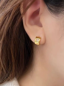 Close-up of heart-shaped zircon gold hoop earring worn by a model for an elegant look