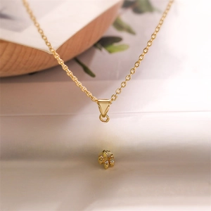 Detail of gold Hamsa hand pendant necklace with green gemstones and zircon stones
